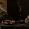 Stacked natural stone jewelry, agarwood bracelet and tea set arranged on linen by a premium spiritual lifestyle brand