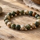 Natural stone bracelet with meaning beside a keepsake pebble and pressed leaf